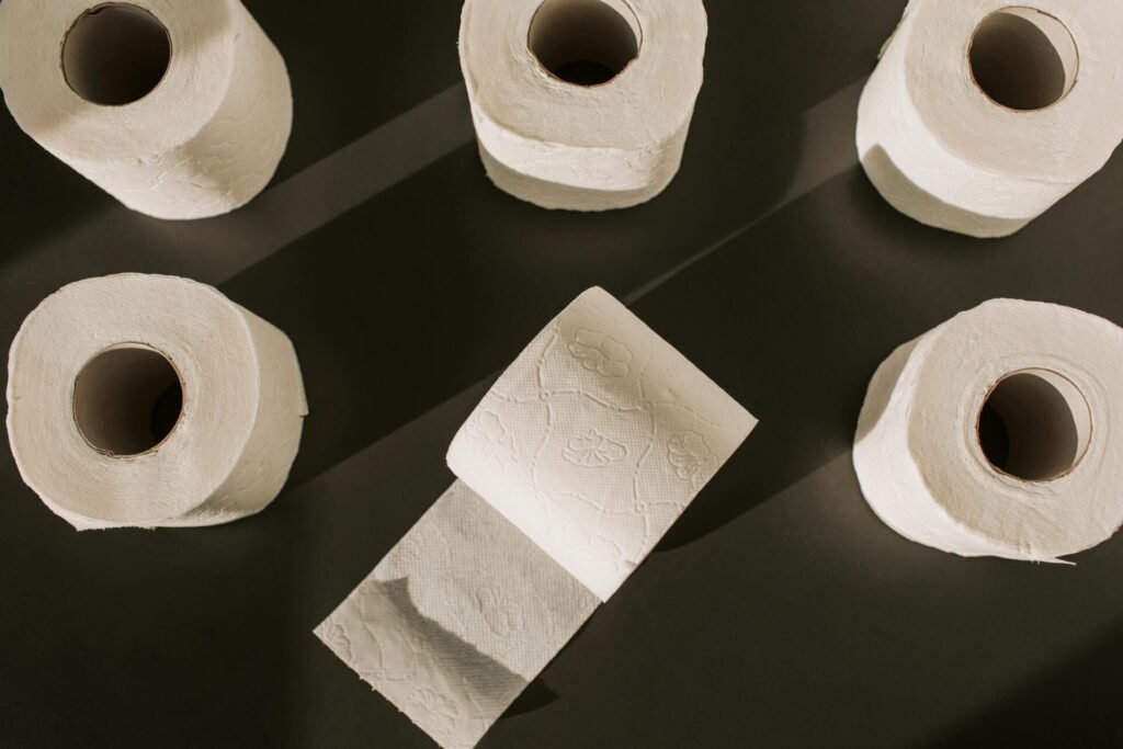 Flat lay of multiple toilet paper rolls on a dark background, artistically arranged.